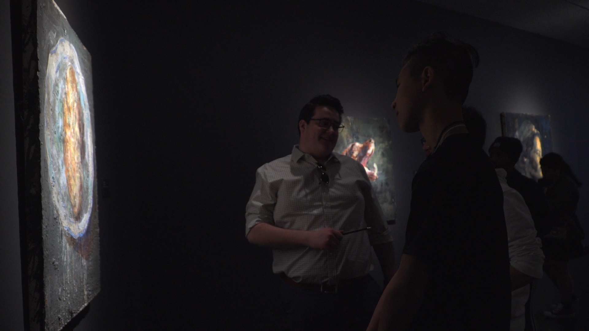 Alexander Morin et Troy Cheah en discussion sur les oeuvres de l’exposition devant une toile de Tony Scherman.